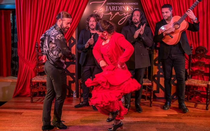 Flamenco dancers performing at Tablao Jardines de Zoraya with musicians in the background.