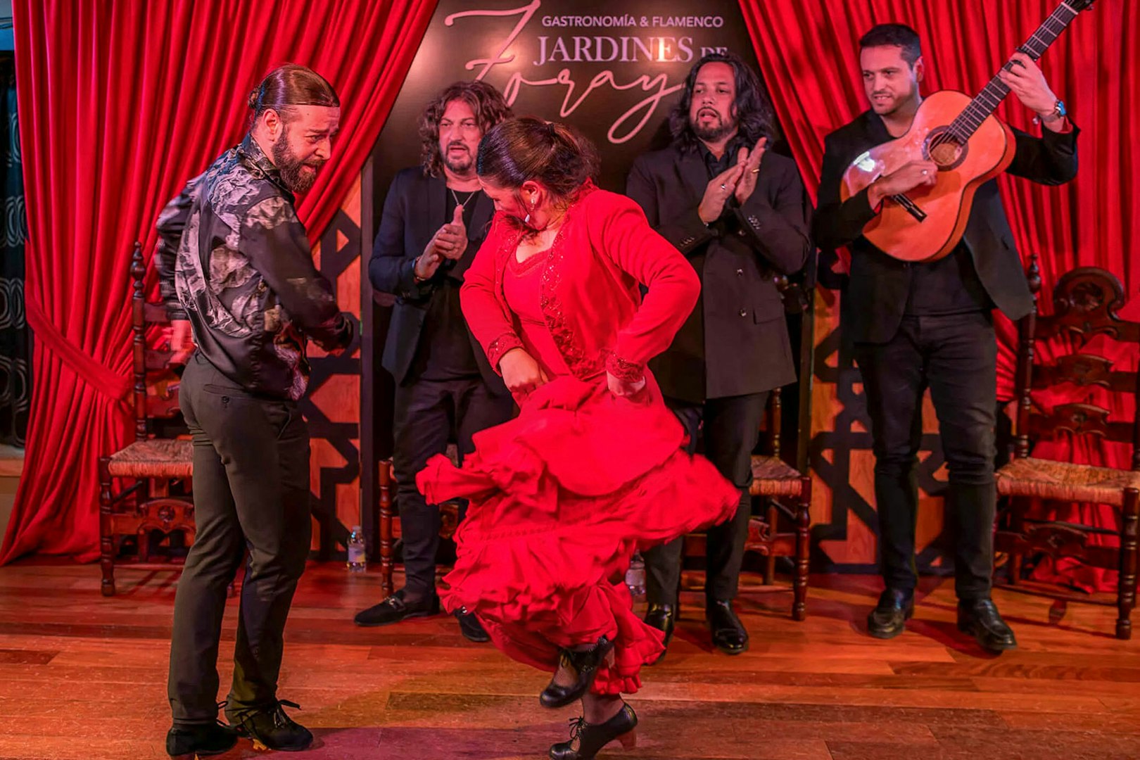 Flamenco dancers performing at Tablao Jardines de Zoraya with musicians in the background.