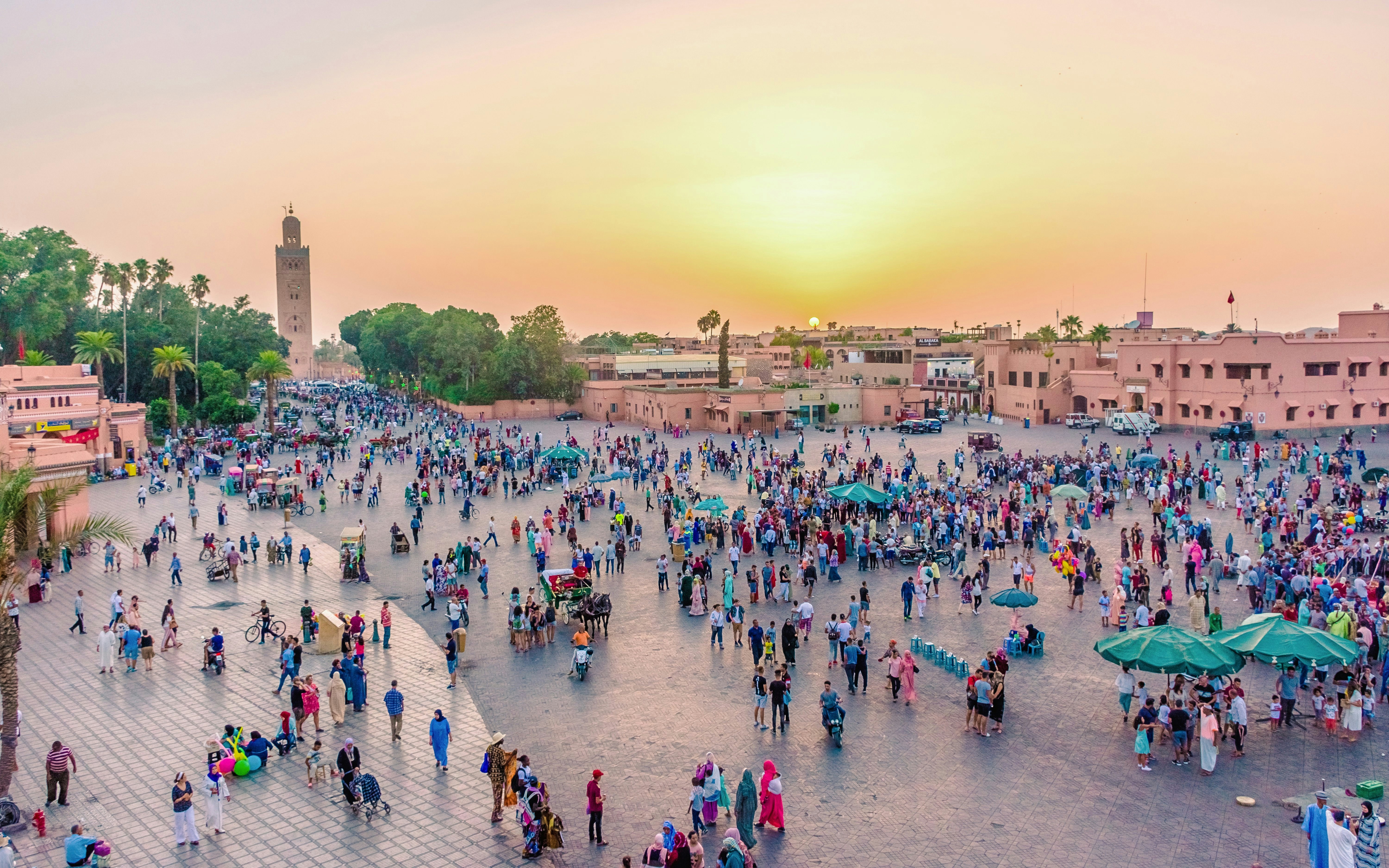 Crowds gather at Jemaa El Fna market square in Marrakech at sunset.