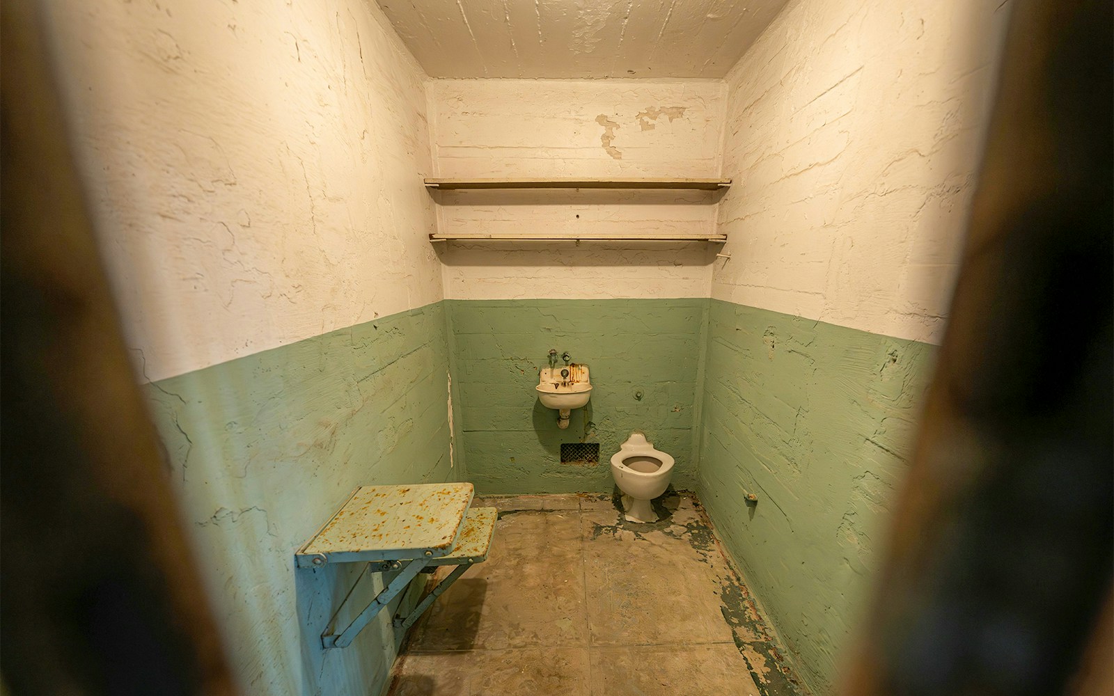 Alcatraz Prison's solitary confinement cell known as "The Hole" with dim lighting and barred door.
