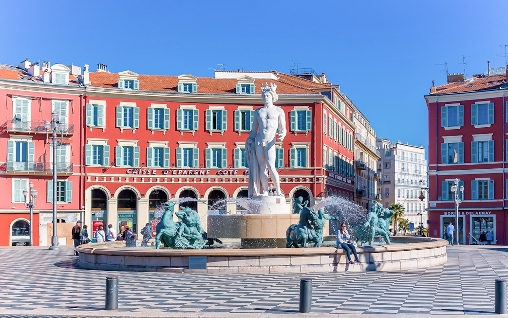 Fountain of the Sun in Place Masséna, Nice, with red buildings in the background.