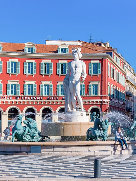 Fountain of the Sun in Place Masséna, Nice, with red buildings in the background.