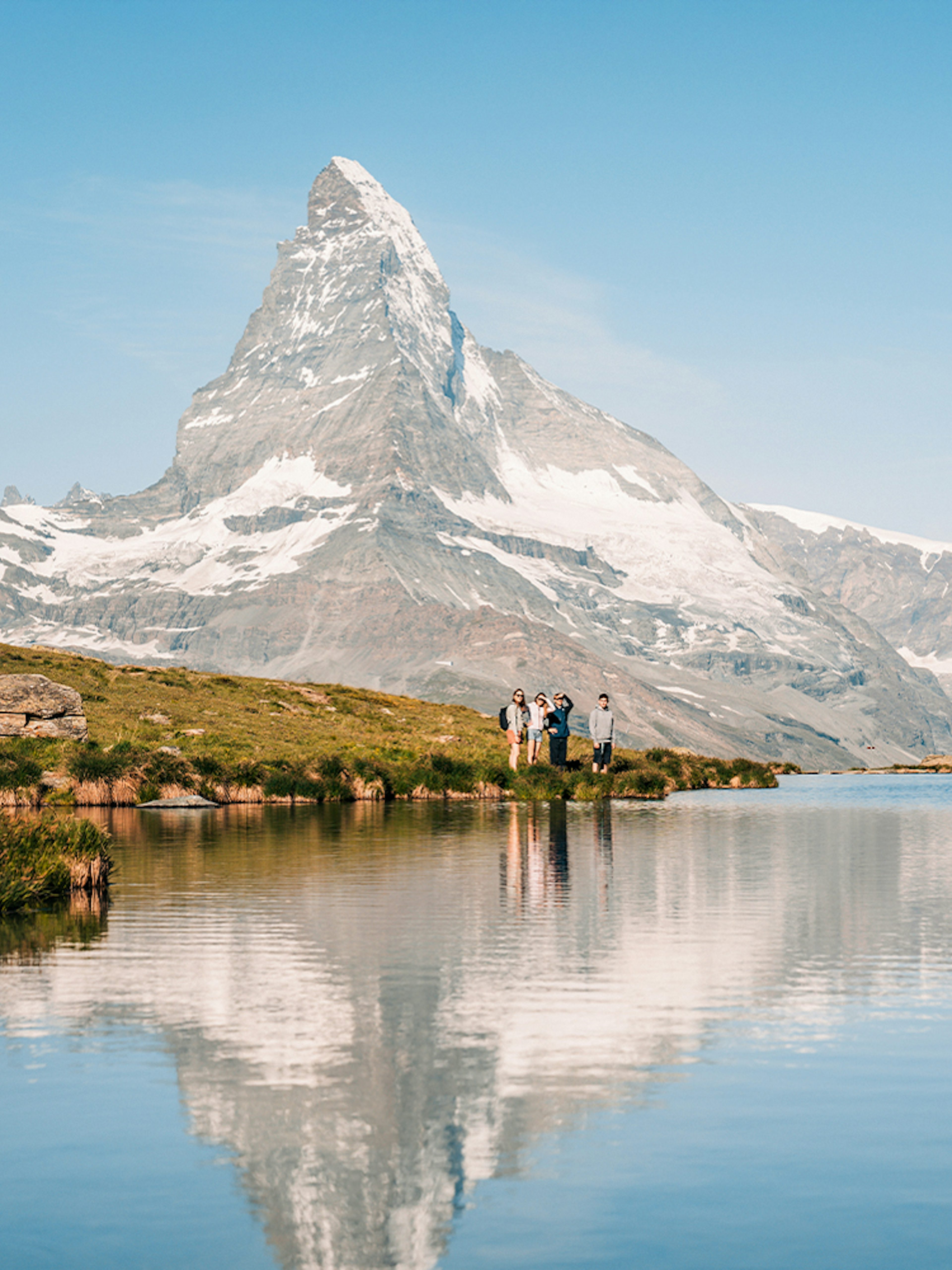 Tourists by Riffelsee Lake with Matterhorn reflection, near Zermatt, Switzerland.