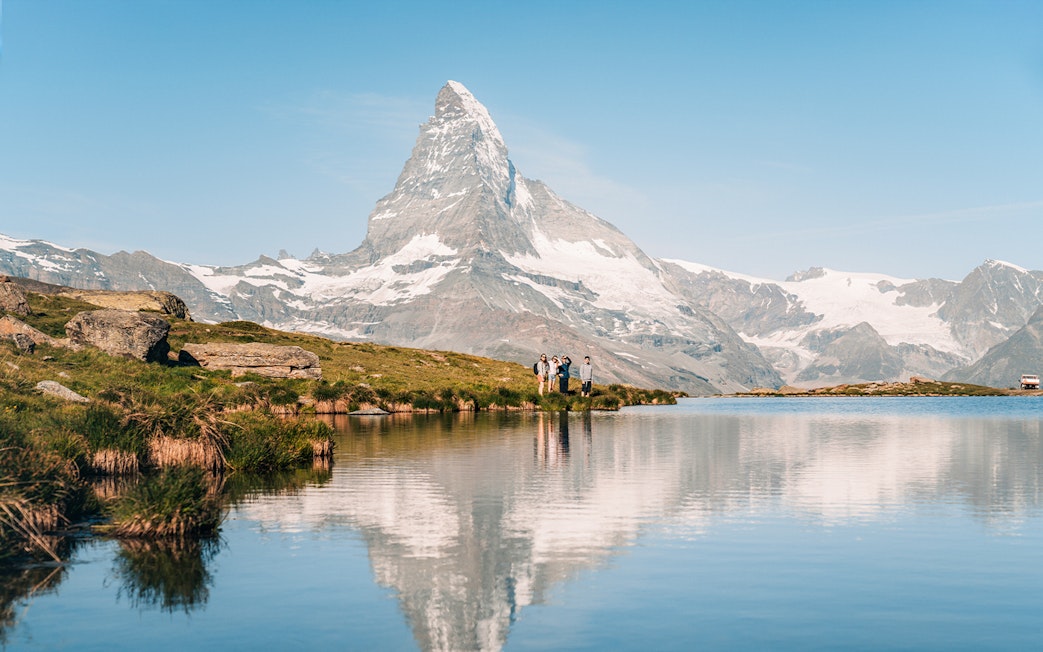Tourists by Riffelsee Lake with Matterhorn reflection, near Zermatt, Switzerland.