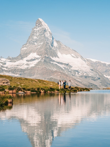 Tourists by Riffelsee Lake with Matterhorn reflection, near Zermatt, Switzerland.