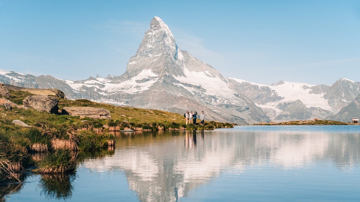 Tourists by Riffelsee Lake with Matterhorn reflection, near Zermatt, Switzerland.