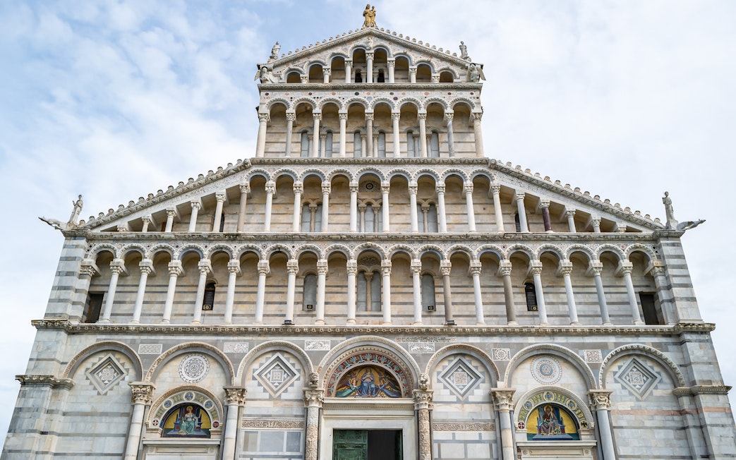Facade of Pisa Cathedral with ornate arches and sculptures.