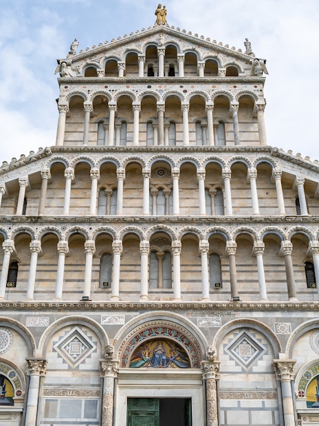 Facade of Pisa Cathedral with ornate arches and sculptures.