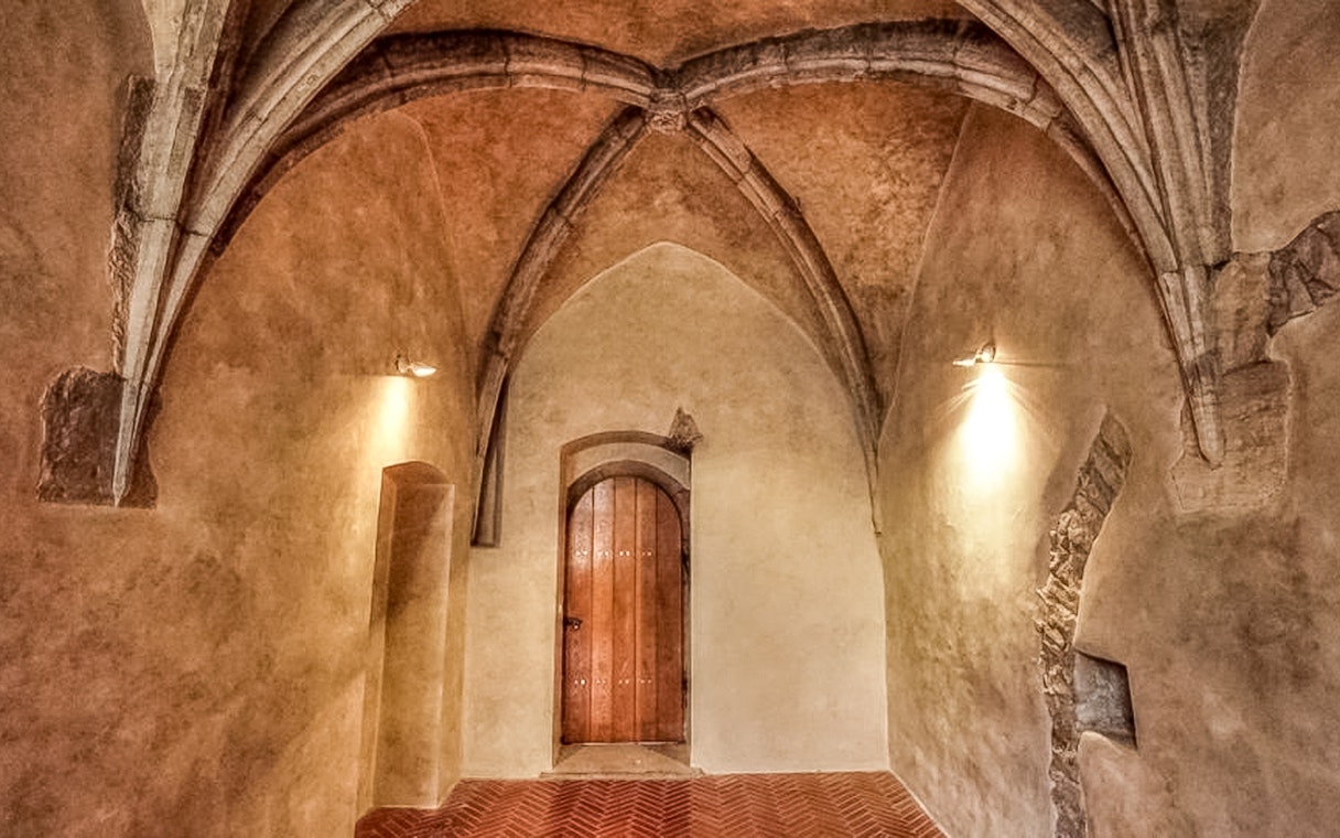 Prague medieval underground chamber with arched ceiling and wooden door.