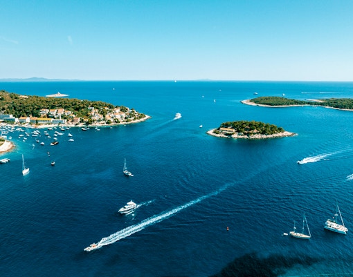 Aerial view of Pakleni Islands, Croatia, with boats navigating the clear blue waters.