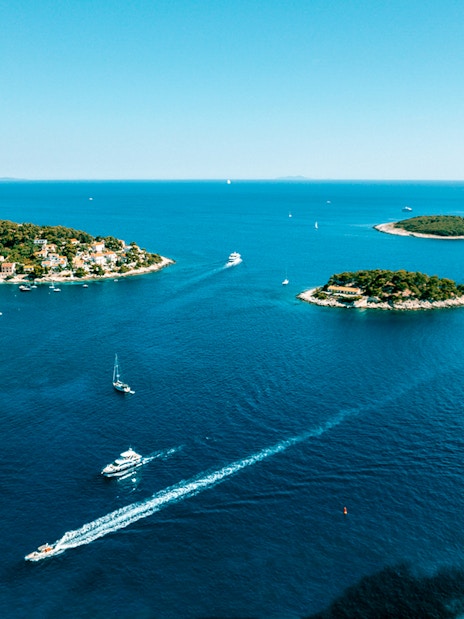 Aerial view of Pakleni Islands, Croatia, with boats navigating the clear blue waters.