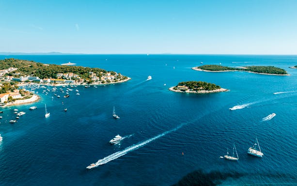 Aerial view of Pakleni Islands, Croatia, with boats navigating the clear blue waters.