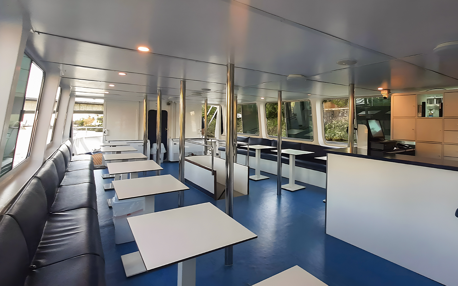 Interior seating area of Seville Guadalquivir River sightseeing cruise with tables and benches.