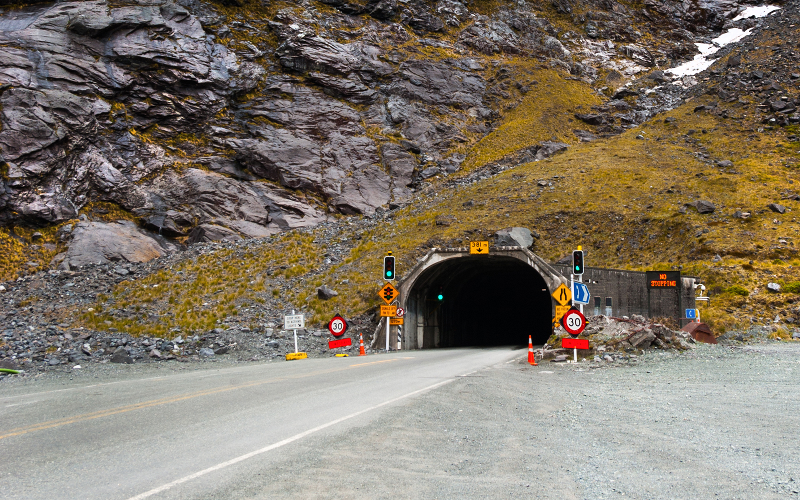 Homer Tunnel entrance with scenic view of Milford Sound fjord and surrounding mountains.