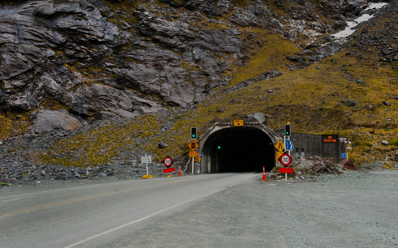 Homer Tunnel entrance with scenic view of Milford Sound fjord and surrounding mountains.
