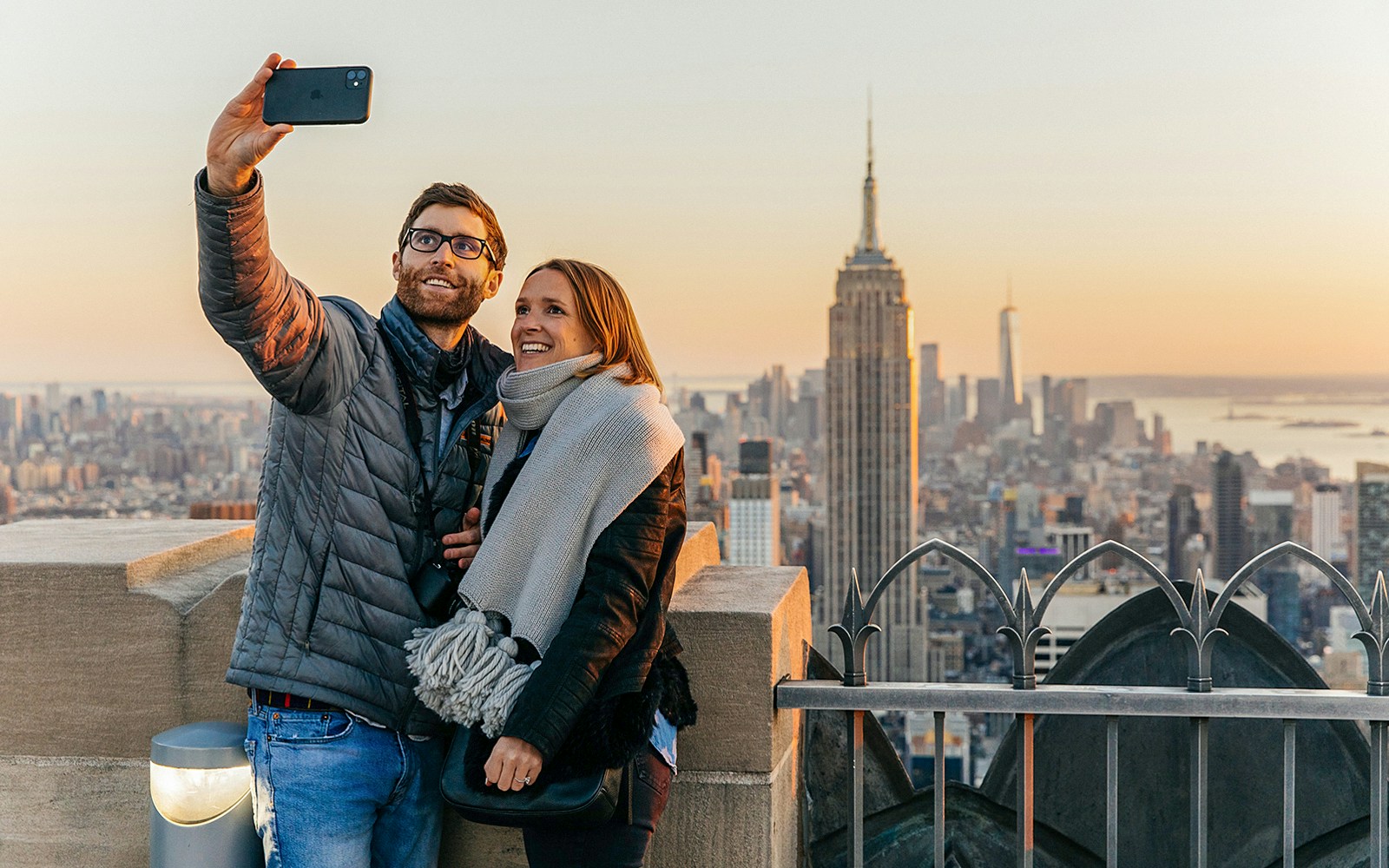 Couple taking selfie with Empire State Building in background at Top of the Rock, Rockefeller Center, New York.