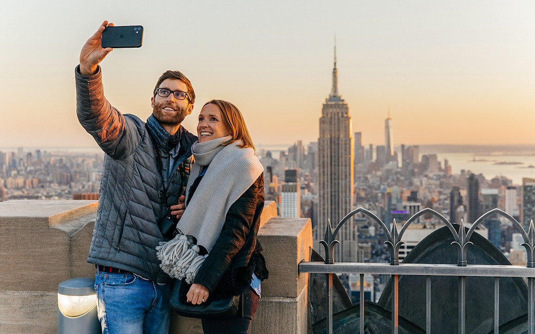 Couple taking a selfie with Empire State Building from Top of the Rock, New York City.
