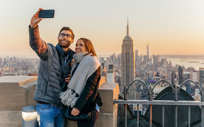Couple taking a selfie with Empire State Building from Top of the Rock, New York City.