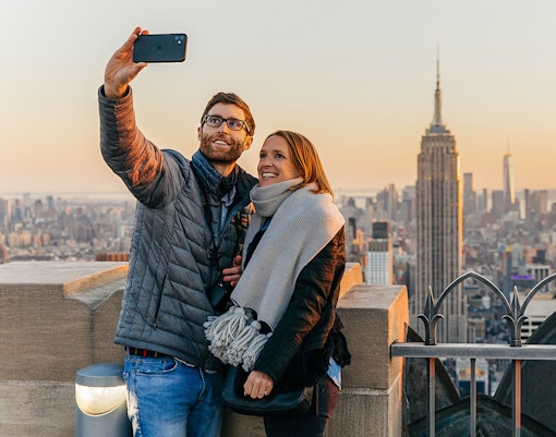 Couple taking selfie with Empire State Building in background at Top of the Rock, Rockefeller Center, New York.