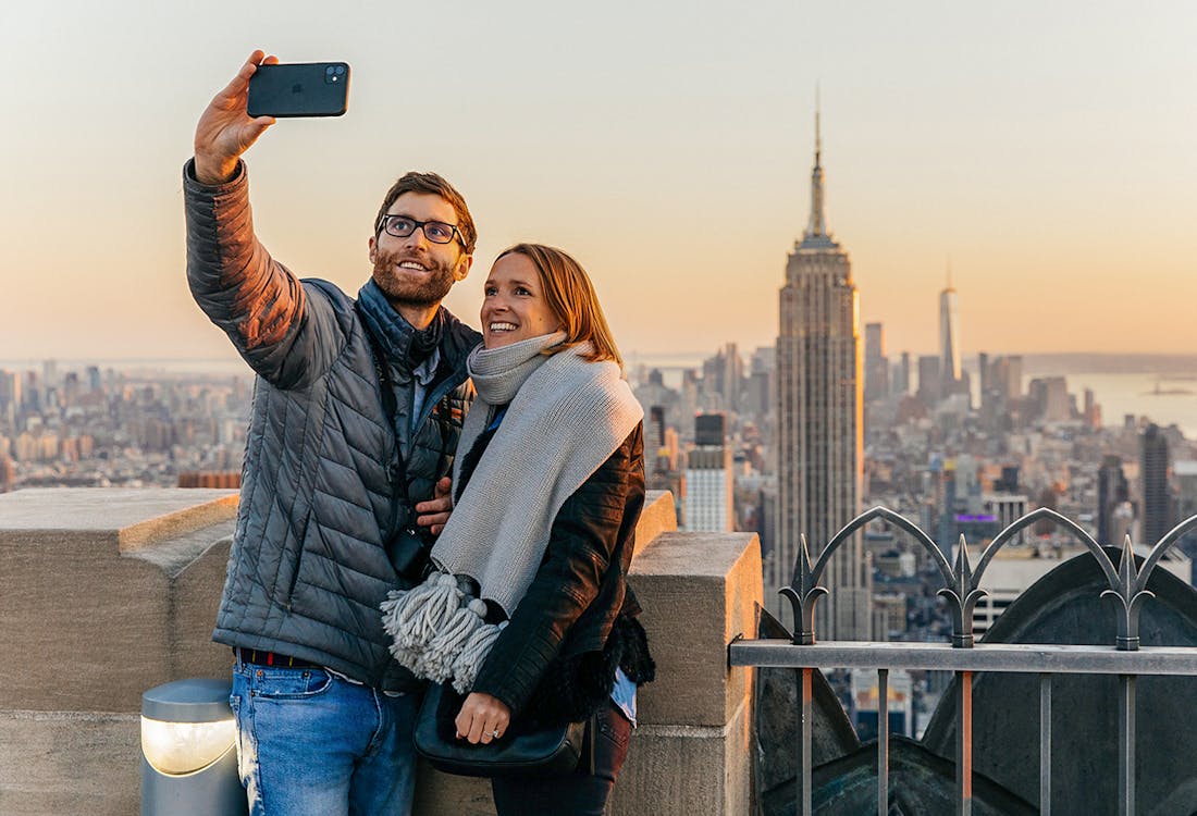 Couple taking selfie with Empire State Building in background at Top of the Rock, Rockefeller Center, New York.