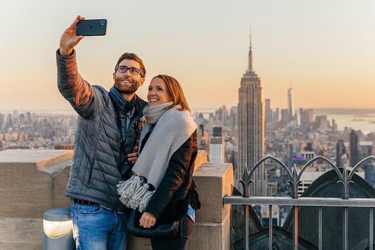 Couple taking selfie with Empire State Building in background at Top of the Rock, Rockefeller Center, New York.