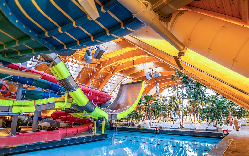 Therme Bucuresti indoor water slides and pool area with tropical plants.