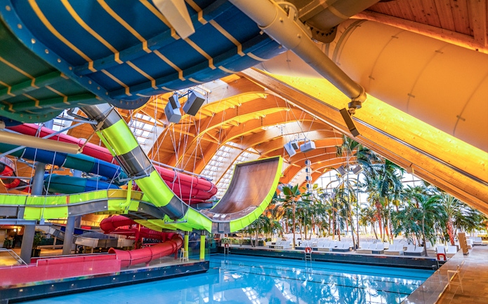 Therme Bucuresti indoor water slides and pool area with tropical plants.