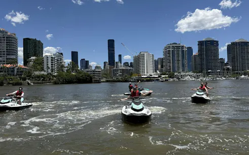 Jet skis on Brisbane River with city skyline in the background.