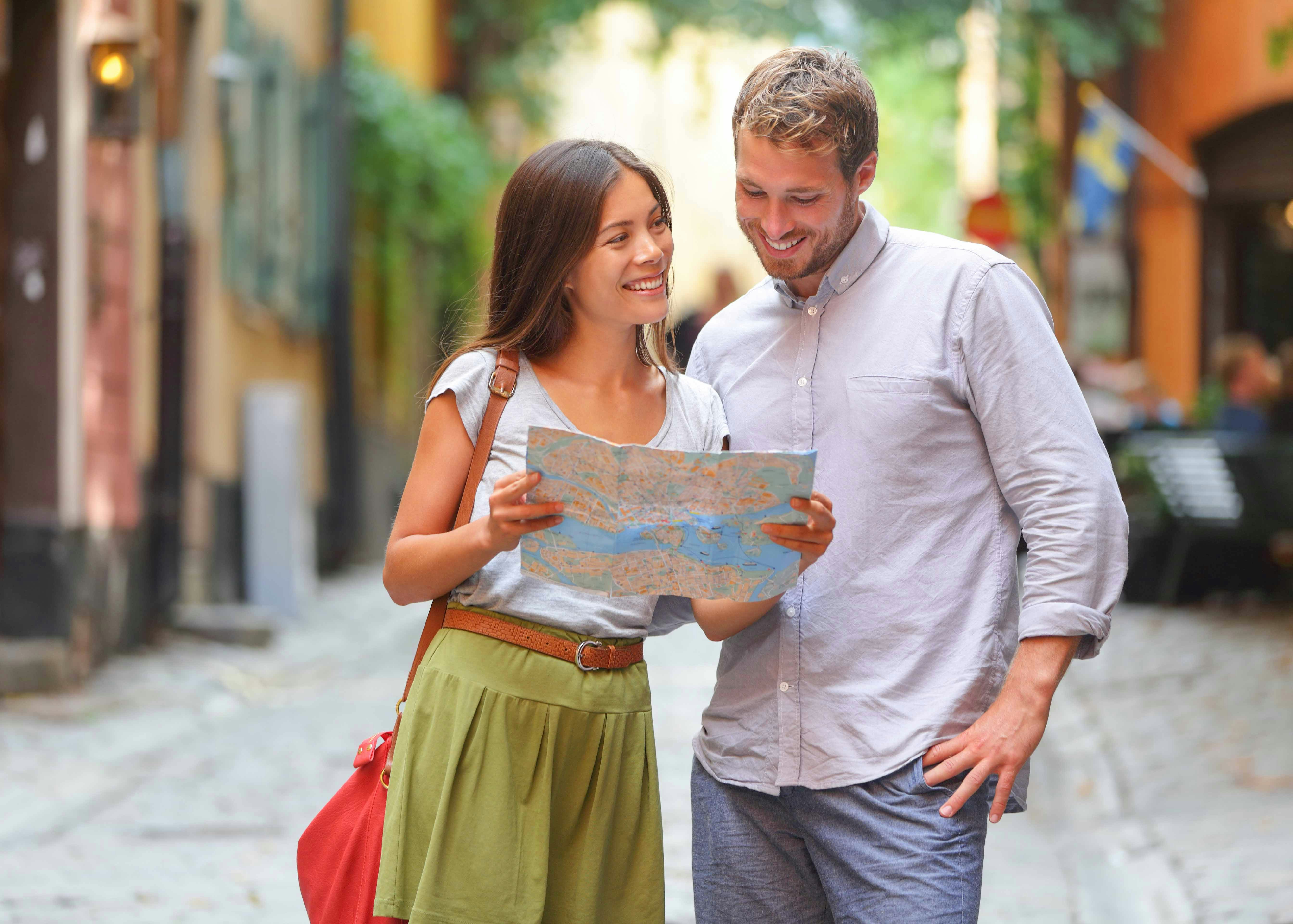 A couple holding a map of the area in hands, navigating through the way
