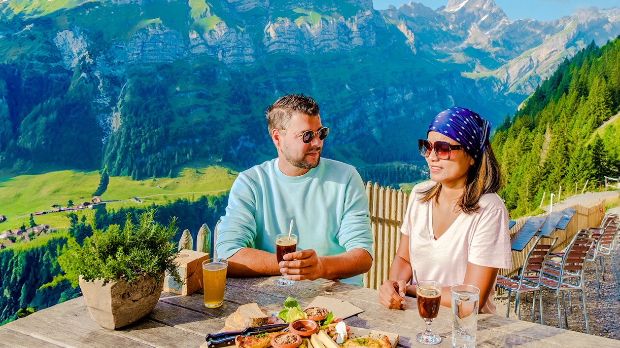 Couple dining at Harder Kulm restaurant with panoramic mountain view in Switzerland.