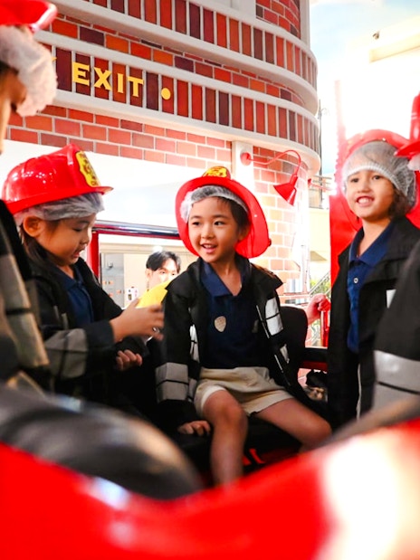 Children in firefighter uniforms at KidZania playing a fire rescue role.