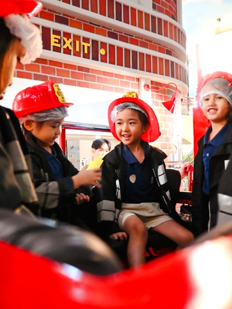 Children in firefighter uniforms at KidZania playing a fire rescue role.