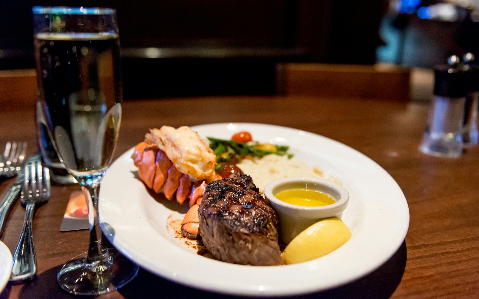 Dinner photo with plates and forks of Steak and a glass of Champagne