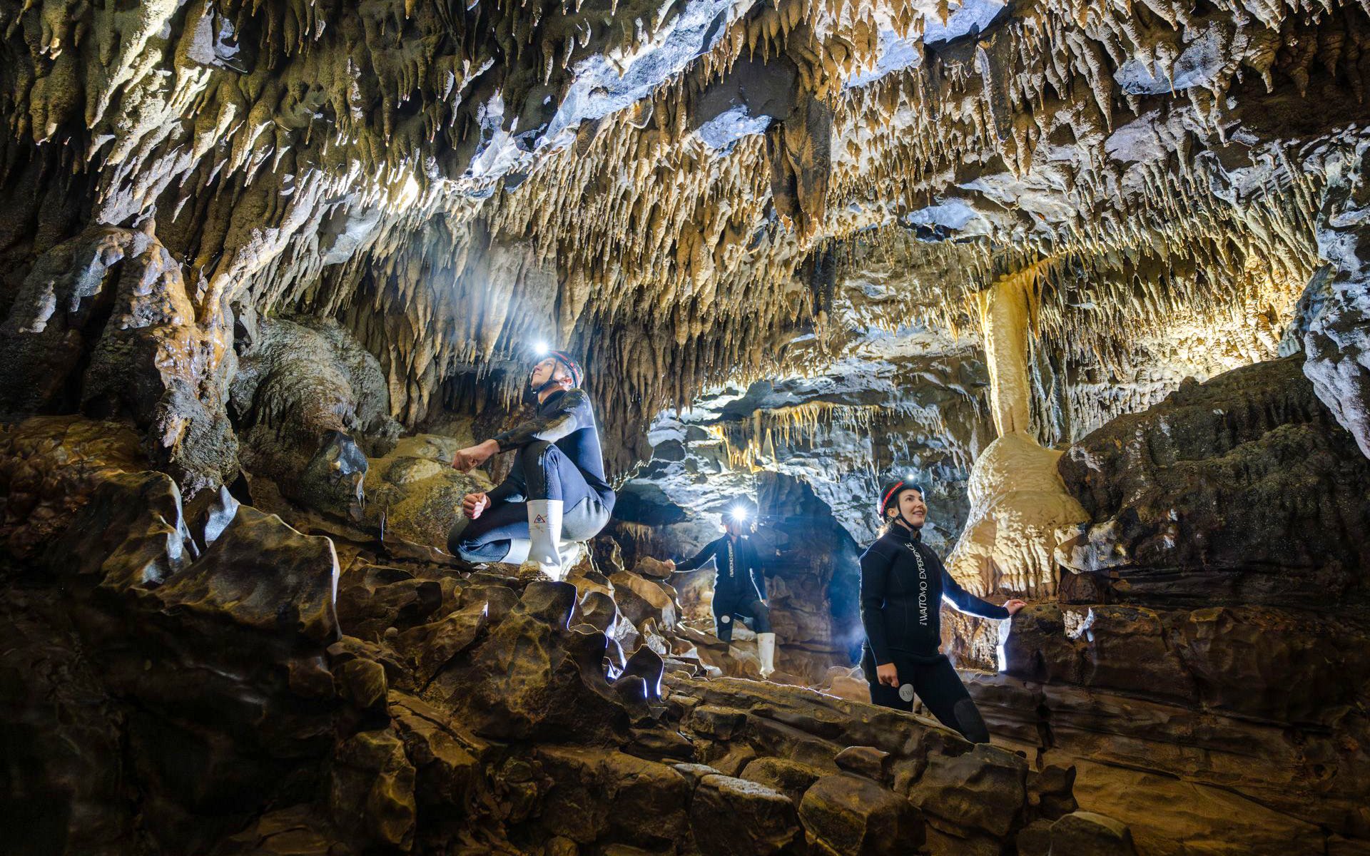 Explorers in Okohua Glowworm Cave, Waitomo, viewing stalactites and rock formations.