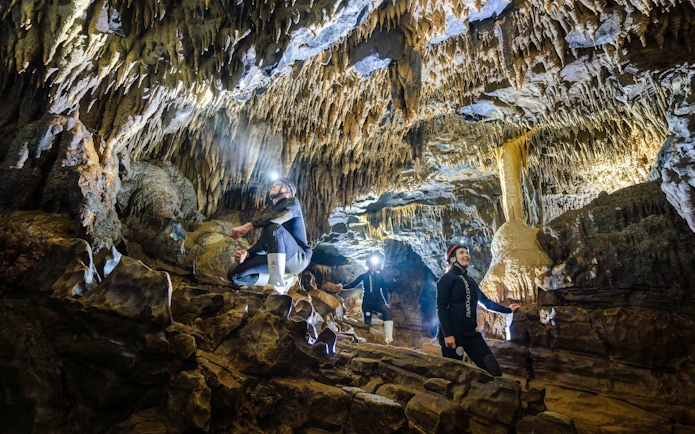 Explorers in Okohua Glowworm Cave, Waitomo, viewing stalactites and rock formations.