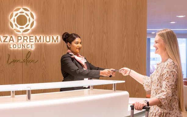 Plaza Premium Lounge staff assisting traveler at London Heathrow Terminal 4.