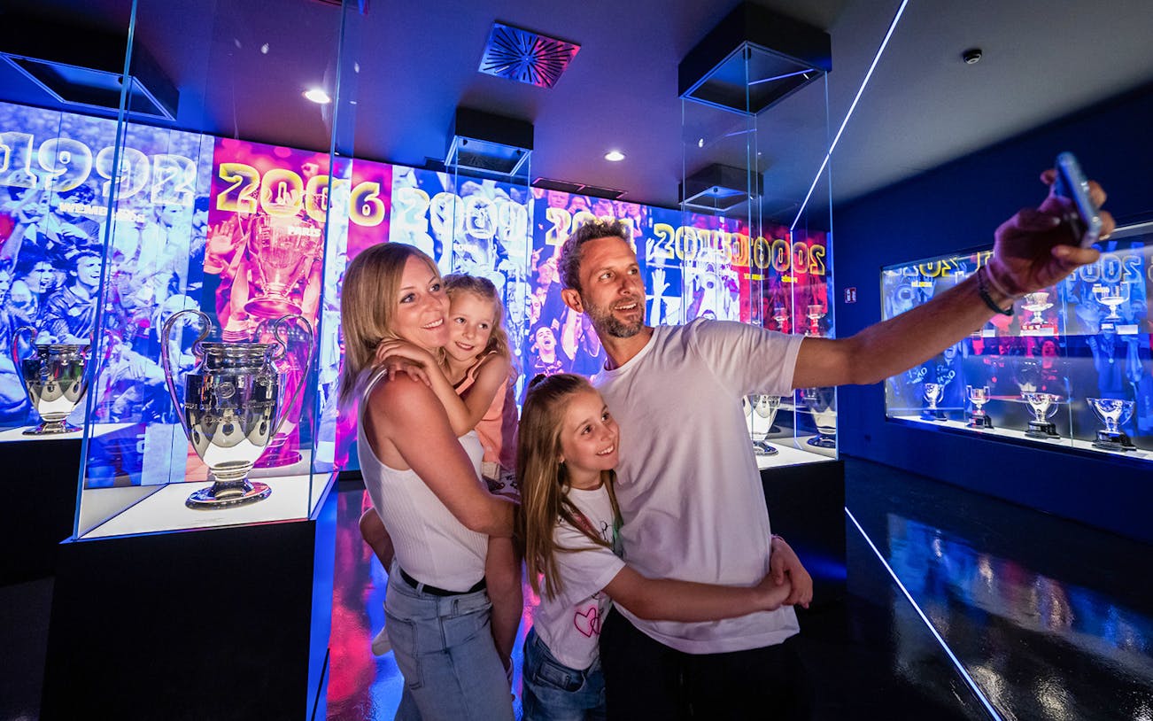 Family taking selfie at FC Barcelona Palau tour with trophy displays in background.