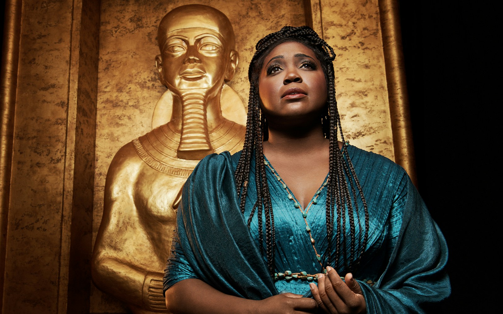 Performer in front of a golden Egyptian statue, related to Aida.