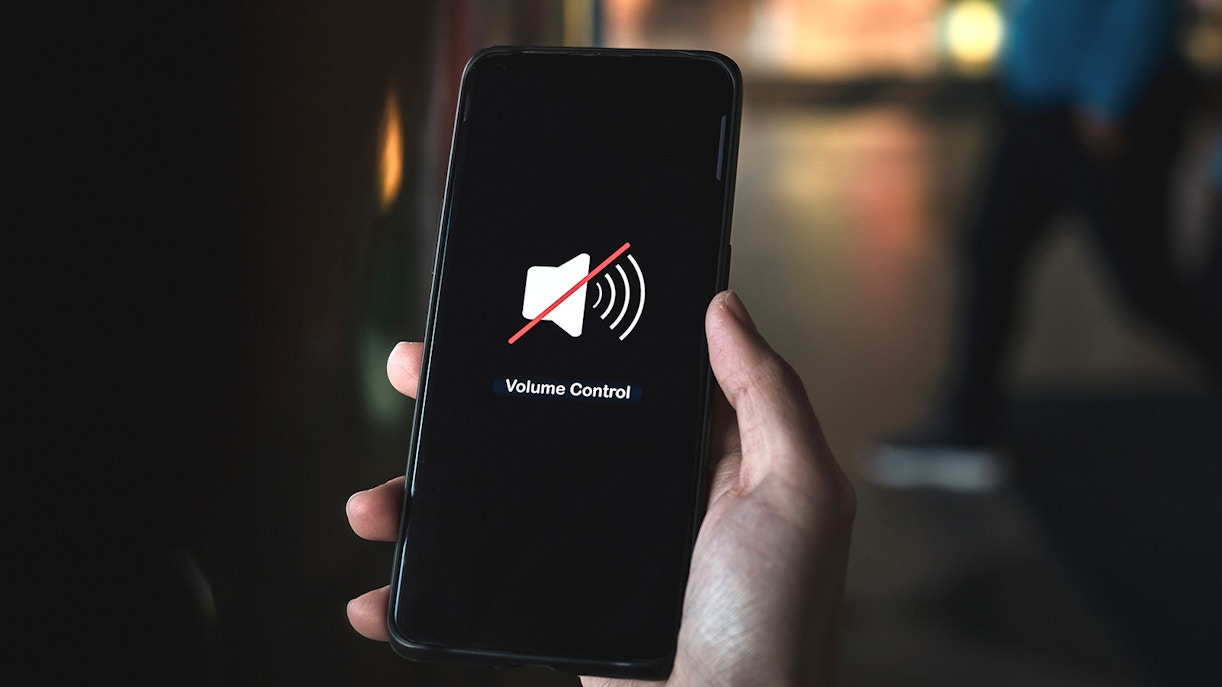 Hand pressing volume of the smartphone in silent or mute mode activated.