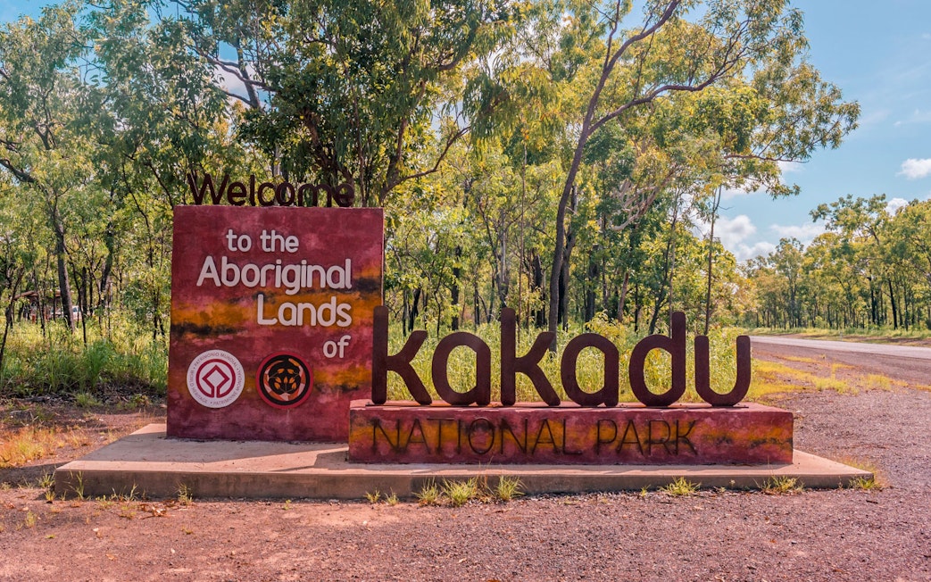 Welcome sign to Kakadu National Park, Aboriginal Lands, surrounded by trees.