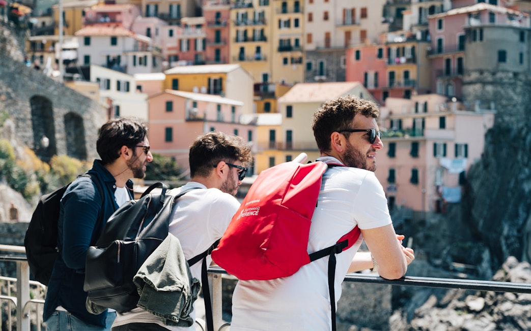 Tourists enjoying the view of colorful buildings in Cinque Terre, Italy.