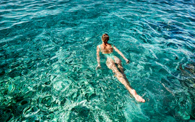 Person swimming in clear blue waters during a Capri boat tour.