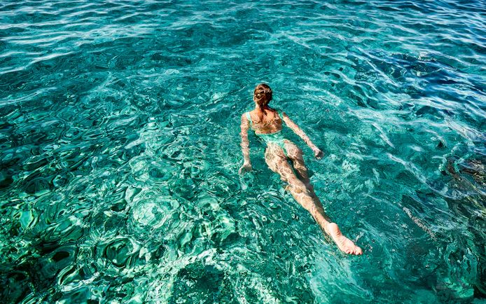 Person swimming in clear blue waters during a Capri boat tour.