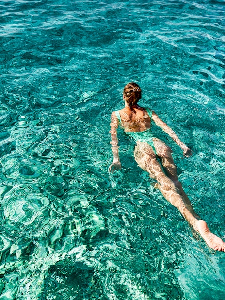 Person swimming in clear blue waters during a Capri boat tour.