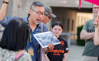 Tour guide showing historical photo during Berlin walking tour on Third Reich and Cold War.