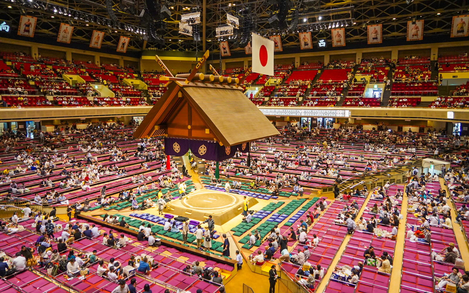 Sumo wrestling event inside Ryogoku arena, Tokyo, with audience seated around the ring.
