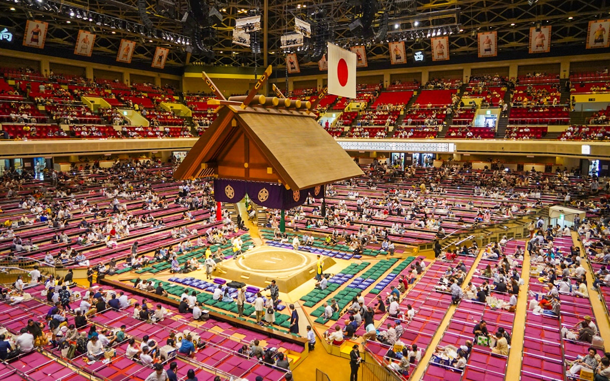 Sumo wrestling event inside Ryogoku arena, Tokyo, with audience seated around the ring.