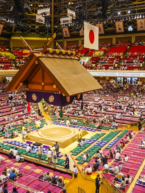 Sumo wrestling event inside Ryogoku arena, Tokyo, with audience seated around the ring.