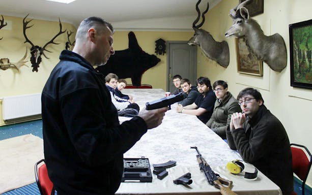 Instructor demonstrating handgun to group at Gdansk shooting range.