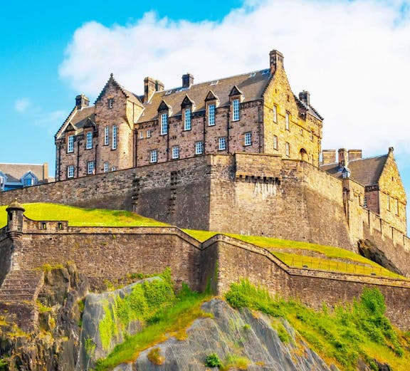 Edinburgh Castle on Castle Rock, Scotland, under a clear blue sky.
